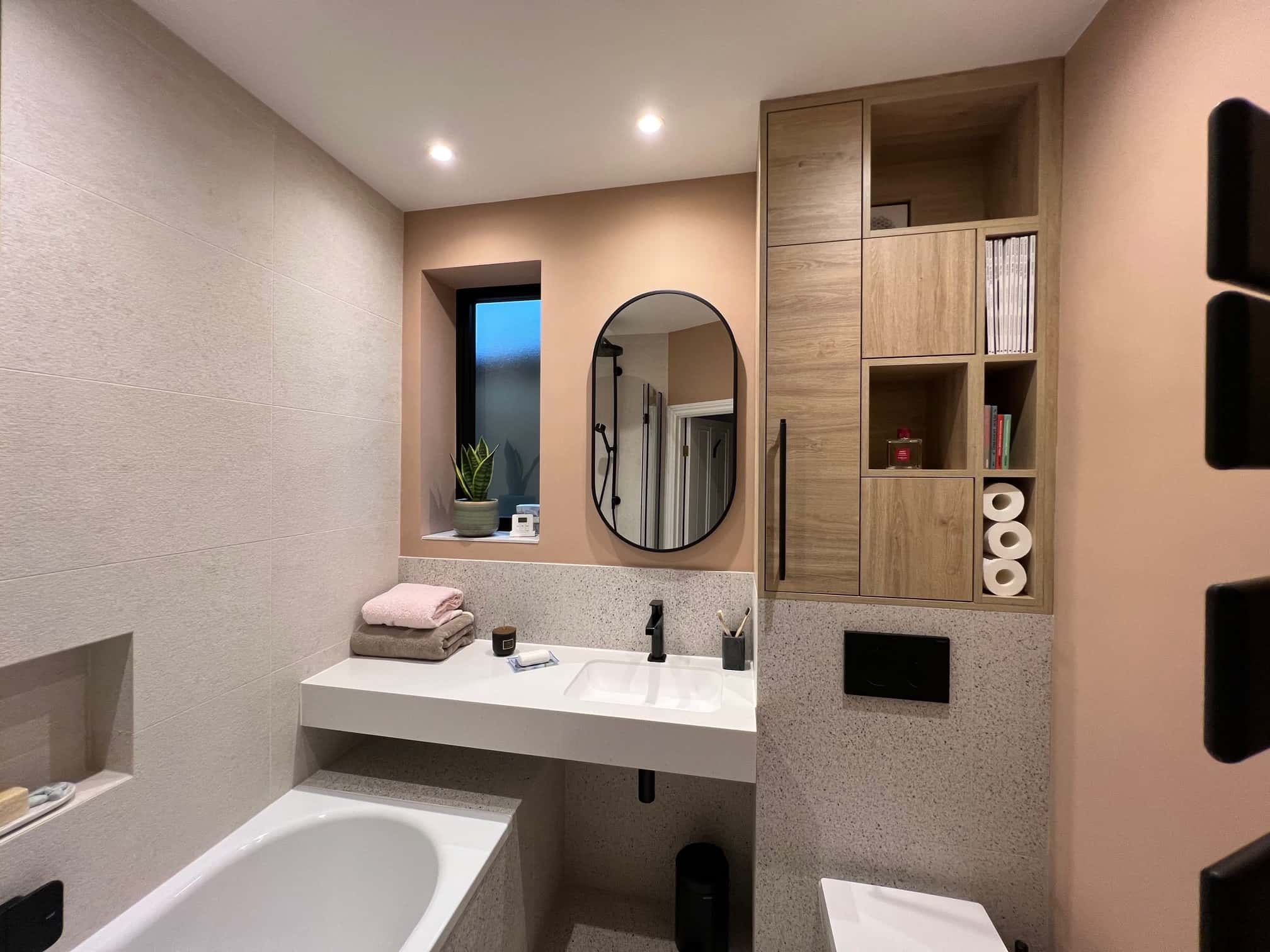 Completed bathroom renovation in Northfields, Ealing — vanity with oval mirror and bespoke timber cabinet