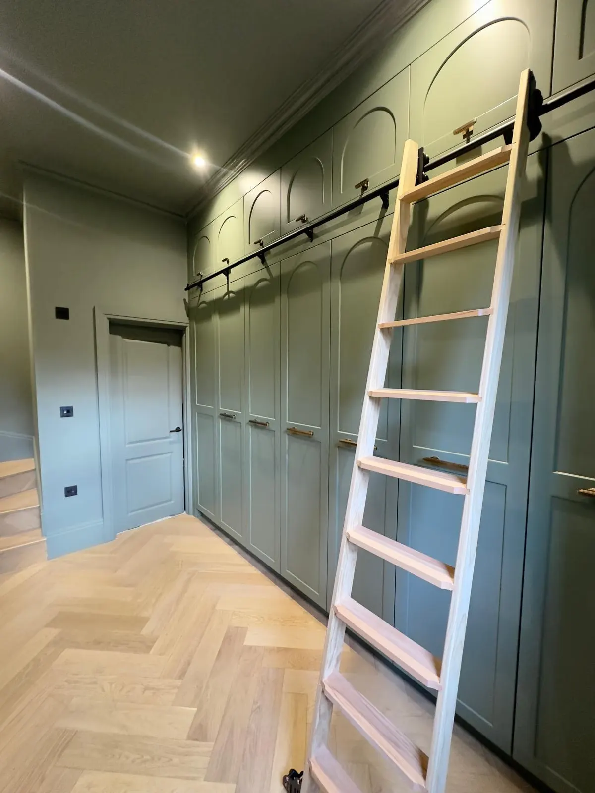 Full-height dressing room with arched top cupboards and a rail ladder