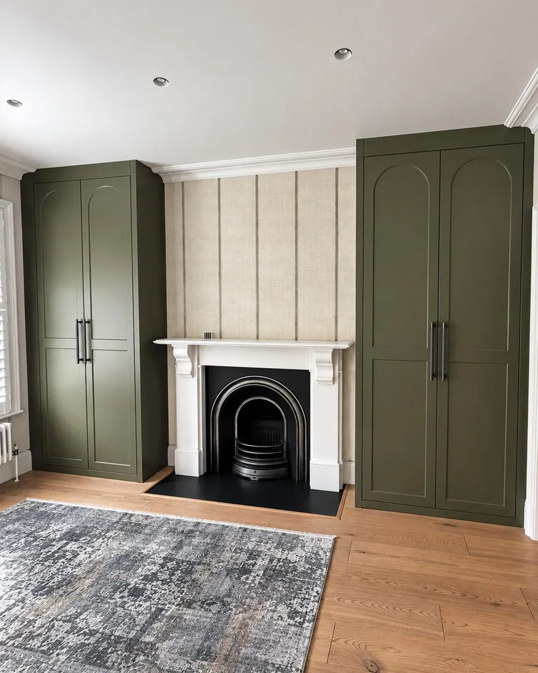 Painted wardrobes built into both alcoves beside a fireplace